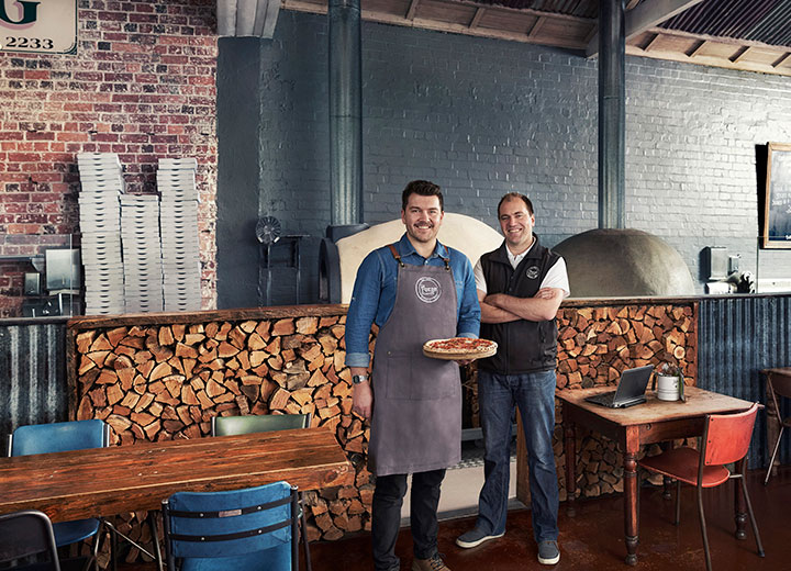 small pizza shop owner is smiling with a nbn technician